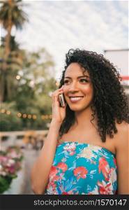 Portrait of young afro american latin woman talking on the phone outdoors in the street. Technology concept.