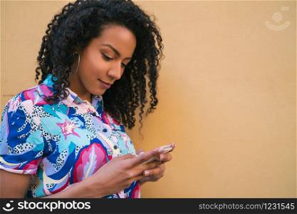 Portrait of young afro american latin woman using her mobile phone and sending messages. Technology concept.