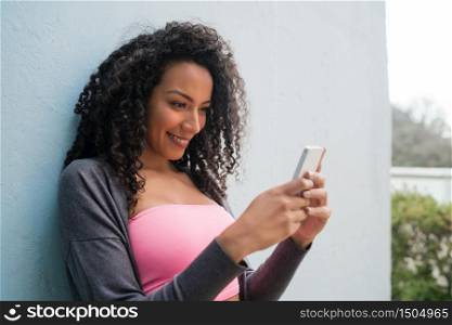 Portrait of young afro american latin woman using her mobile phone and sending messages. Communication concept.