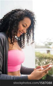 Portrait of young afro american latin woman using her mobile phone and sending messages. Communication concept.