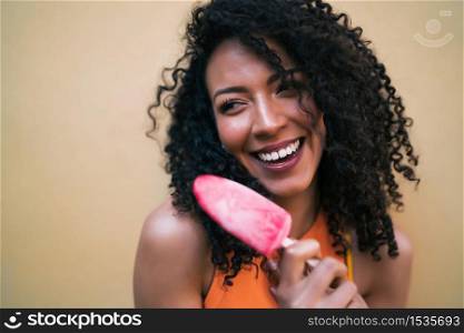 Portrait of young afro american woman enjoying summertime and eating an ice-cream. Lifestyle concept.