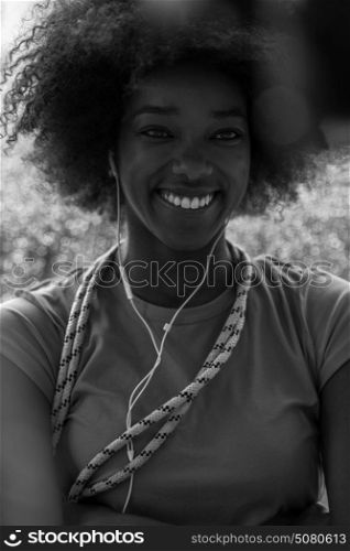 portrait of young afro american woman in gym on workout break while listening music on earphone and dancing rainy day and bad weather outdooor
