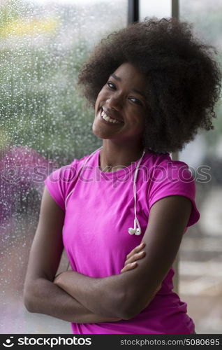 portrait of young afro american woman in gym on workout break while listening music on earphone and dancing rainy day and bad weather outdooor