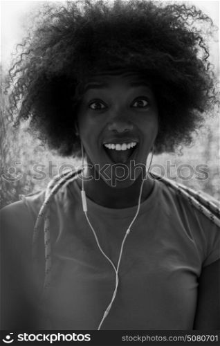 portrait of young afro american woman in gym on workout break while listening music on earphone and dancing rainy day and bad weather outdooor
