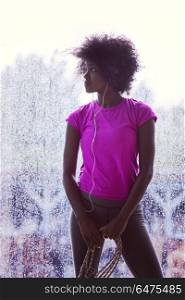 portrait of young afro american woman in gym on workout break while listening music on earphone and dancing rainy day and bad weather outdooor. portrait of young afro american woman in gym while listening mus