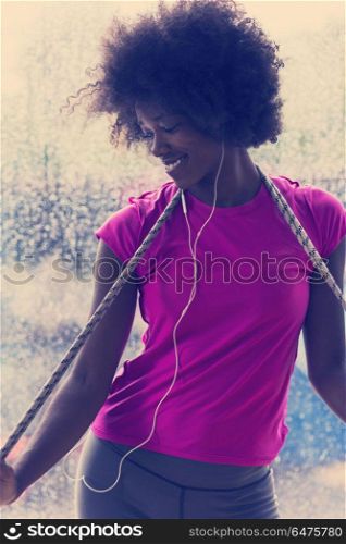 portrait of young afro american woman in gym on workout break while listening music on earphone and dancing rainy day and bad weather outdooor. portrait of young afro american woman in gym while listening mus