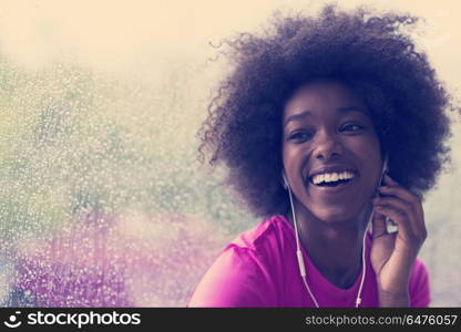 portrait of young afro american woman in gym on workout break while listening music on earphone and dancing rainy day and bad weather outdooor. portrait of young afro american woman in gym while listening mus