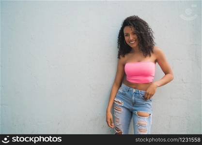 Portrait of young afro american woman looking confident and posing against grey background.