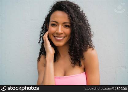 Portrait of young afro american woman looking confident and posing against grey background.