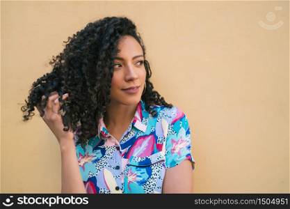 Portrait of young afro american woman looking confident and posing against yellow background.
