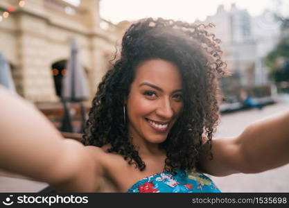 Portrait of young afro american woman taking a selfie outdoors in the street. Enjoying life. Lifestyle concept.