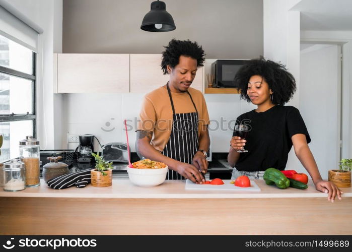 Portrait of young afro couple cooking together in the kitchen at home. Relationship, cook and lifestyle concept.