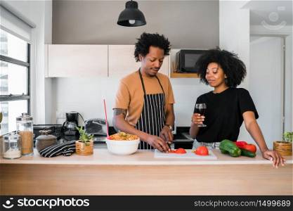 Portrait of young afro couple cooking together in the kitchen at home. Relationship, cook and lifestyle concept.