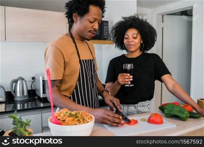 Portrait of young afro couple cooking together in the kitchen at home. Relationship, cook and lifestyle concept.