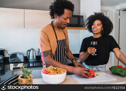 Portrait of young afro couple cooking together in the kitchen at home. Relationship, cook and lifestyle concept.