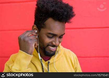 Portrait of young afro man enjoying and listening to music with earphones. Technology and lifestyle concept.