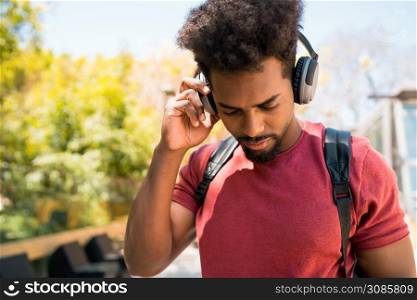 Portrait of young afro man enjoying and listening to music with headphones. Technology and lifestyle concept.
