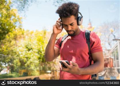 Portrait of young afro man enjoying and listening to music with his mobile phone. Technology and lifestyle concept.