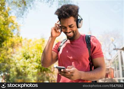 Portrait of young afro man enjoying and listening to music with his mobile phone. Technology and lifestyle concept.