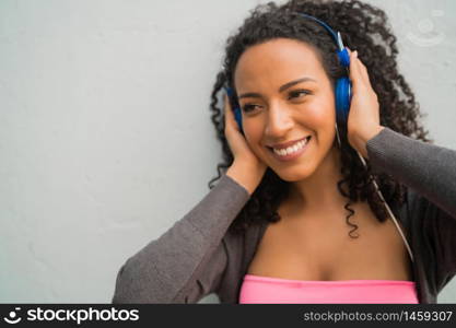 Portrait of young afro woman enjoying and listening to music with blue headphones. Technology and lifestyle concept.