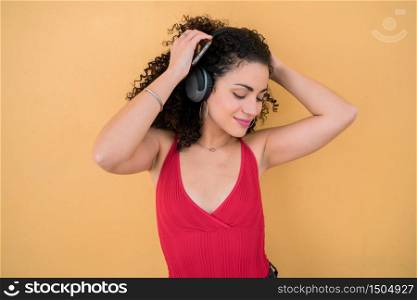 Portrait of young afro woman enjoying and listening to music with headphones. Technology and lifestyle concept.