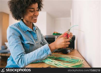 Portrait of young afro woman fixing electricity problem with cables at new home. Repair and renovation home concept.