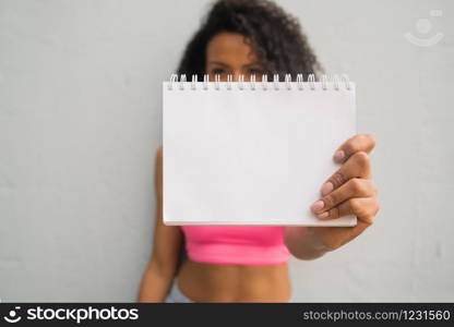 Portrait of young afro woman holding a blank paper. Showing or promoting something. Advertising concept.