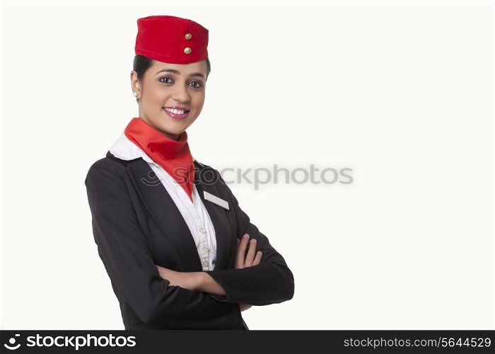 Portrait of young air hostess with arms crossed standing against white background