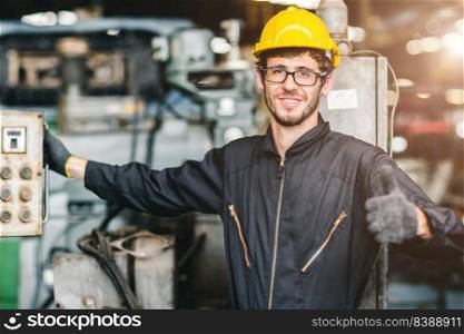 Portrait of young American happy worker enjoy happy smiling to work in a heavy industrial factory.Thumb up with machine controller.