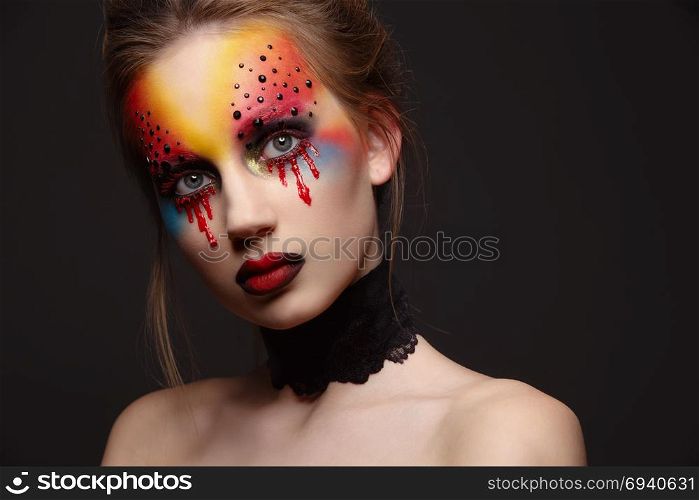 Portrait of young and beauty female model with creative makeup, bloody eyes and black rhinestones. Young female model with bloody eyes makeup