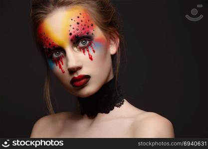 Portrait of young and beauty female model with creative makeup, bloody eyes and black rhinestones. Young female model with bloody eyes makeup