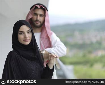 portrait of young arabian muslim couple in traditional clothes standing on balcony representing modern islam fashion and ramadan kareem concept
