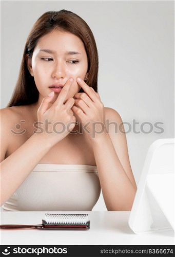 Portrait of young ardent asian woman looking in the mirror worry about pimple on her face. Beauty care for skin problem, acne treatment concept.. Portrait of ardent asian woman looking at mirror worry about pimple.