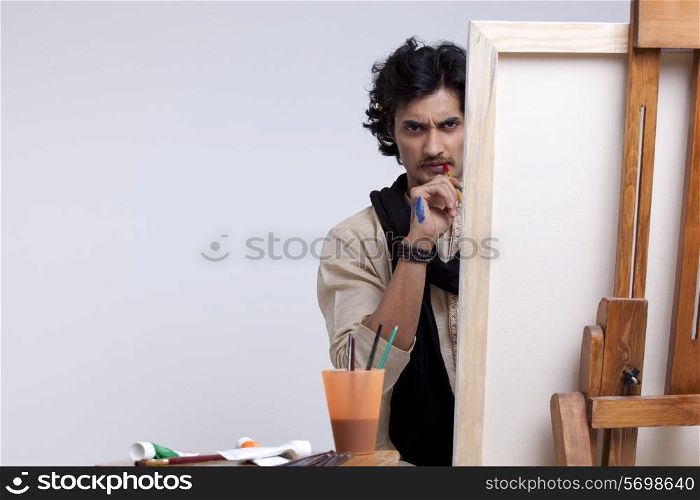 Portrait of young artist contemplating against colored background