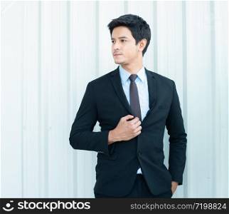portrait of young asian businessman in suit standing in workplace with smart and confident concept isolated on wall backgrounds.