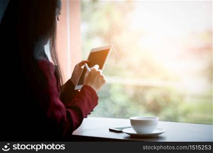Portrait of Young asian businesswoman sitting indoors in cafe using digital tablet with coffee. Business success concept.