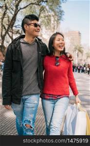 Portrait of young Asian couple in love walking in the city after shopping. Shop concept.