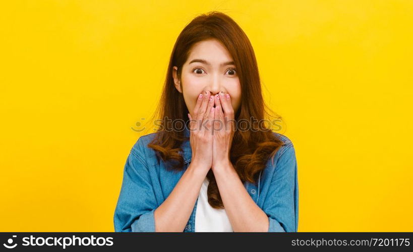 Portrait of young Asian lady with positive expression, joyful surprise funky, dressed in casual clothing and looking at the camera over yellow background. Happy adorable glad woman rejoices success.