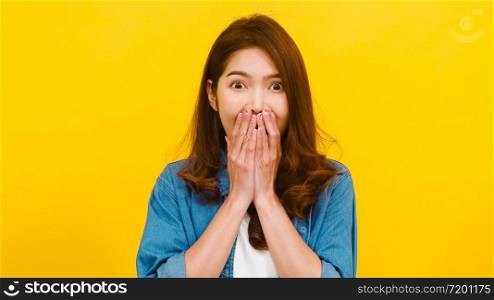 Portrait of young Asian lady with positive expression, joyful surprise funky, dressed in casual clothing and looking at the camera over yellow background. Happy adorable glad woman rejoices success.