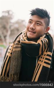 Portrait of young asian man looking confident and wearing winter clothes outdoors in the street. Urban concept.