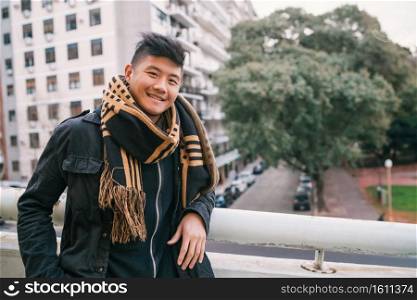 Portrait of young asian man looking confident and wearing winter clothes outdoors in the street. Urban concept.. Portrait of young Asian man outdoors.