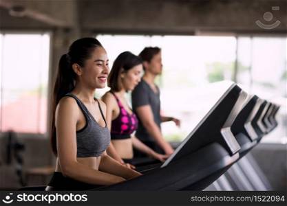 Portrait of young Asian smiling woman with friends running on treadmills in sport fitness gym. Happy women and man run on machine. Cardio exercise, training for healthy lifestyle concept.