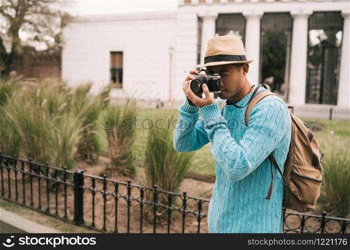 Portrait of young asian tourist with a vintage camera and taking some photos outdoors in the street. Travel concept.