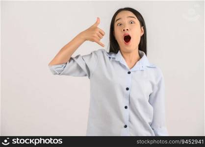 Portrait of young asian woman doing phone gesture like says call me back over isolated white background. Advertising and lifestyle concept.