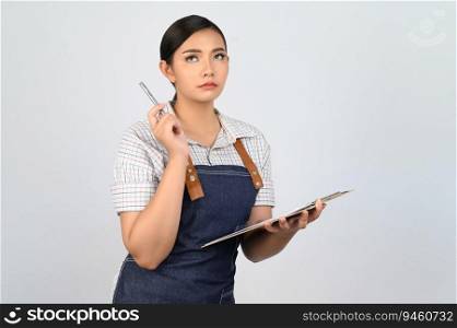Portrait of young asian woman in waitress uniform holding clipboard and pen for checking order, copy space to insert products for advertisement isolated on white background