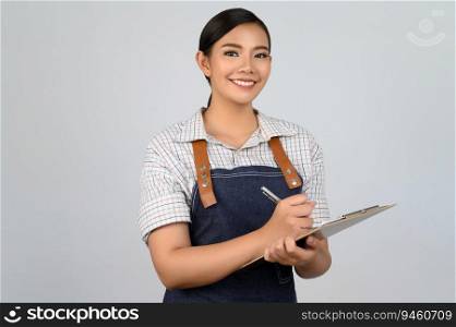 Portrait of young asian woman in waitress uniform holding clipboard for checking order, copy space to insert products for advertisement isolated on white background