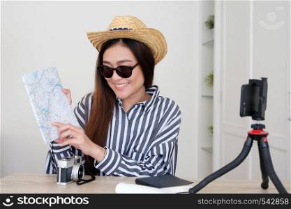 Portrait of young asian woman travel blogger holding map while recording video, live streaming, on social media, blogger and vlogger concept