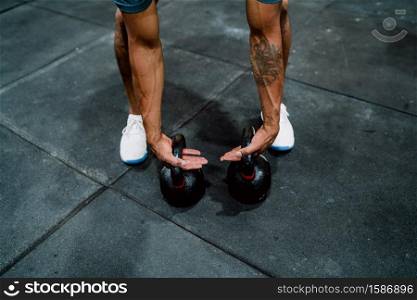 Portrait of young athletic man doing exercise with crossfit kettlebel at the gym. Crossfit, sport and healthy lifestyle concept.