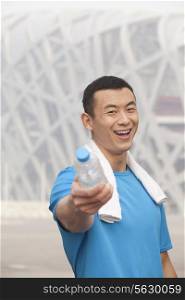 Portrait of young athletic man in Beijing pointing water bottle
