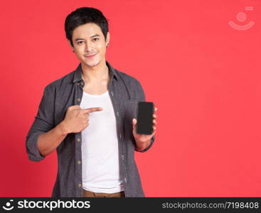 Portrait of young attractive asian businessman or student using mobile phone, laptop, tablet, standing isolated on red background wearing casual shirt look at camera in studio with copy space.